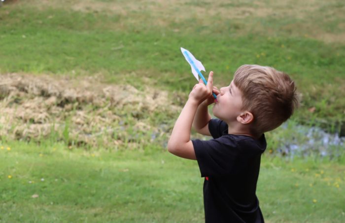 Young male student blowing air into their straw rocket to make it fly.