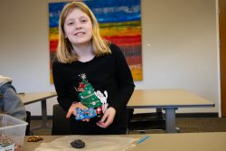 Smiling Lebanon students holds up her mosaic project which is constructed out of blue air-drying clay and various colorful legumes."