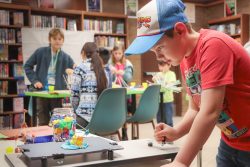Male student testing out their hand-made cardboard structure on a shake table."