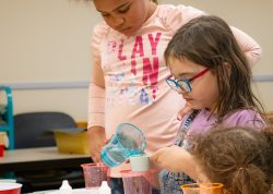 Three young students work together to measure out ingredients for a chemistry project."